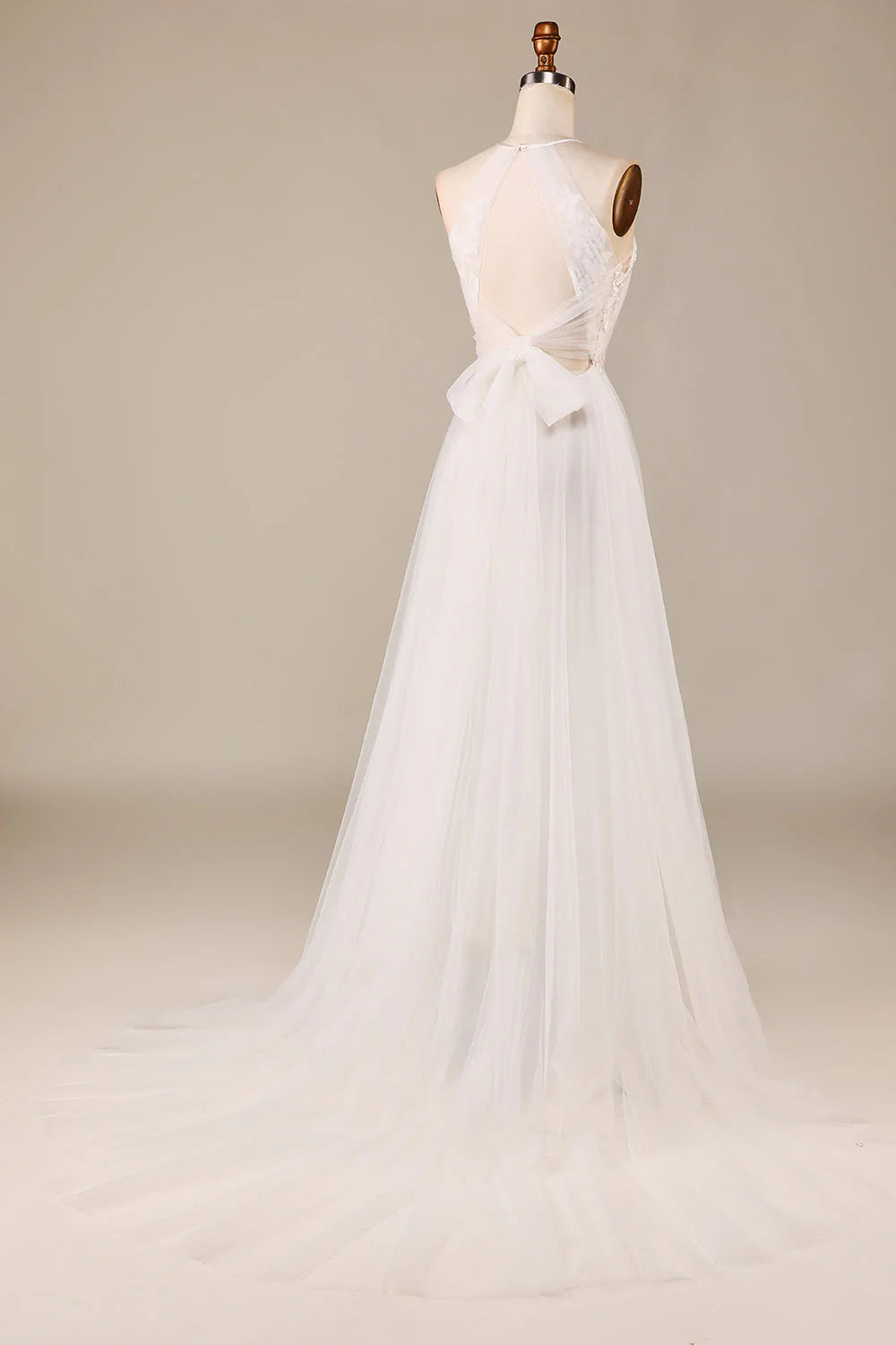 Un grazioso abito da sposa in pizzo trasparente color avorio, senza maniche, con scollatura a trapezio e schiena scoperta.